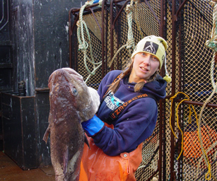 photo of an AFSC geneticist holding a large Pacific cod